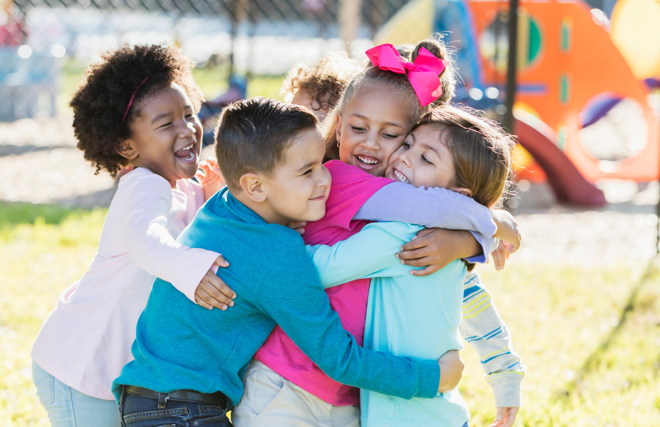 Children playing outdoors on playground, hugging